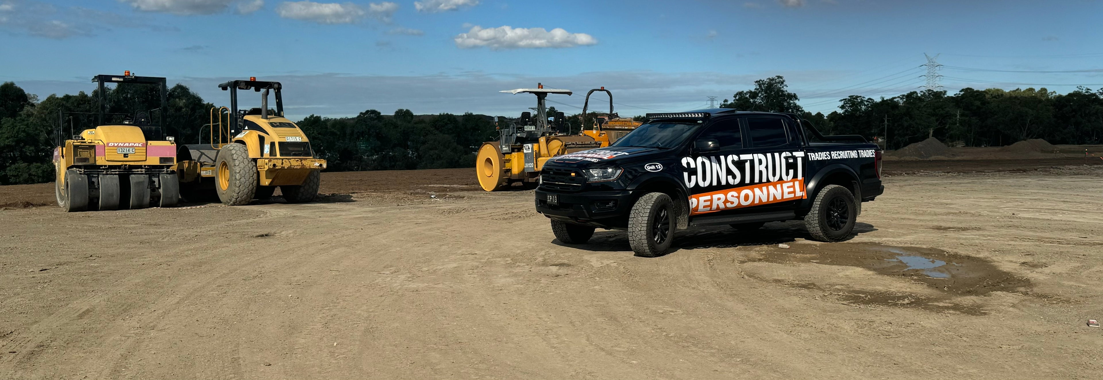 Black pickup truck with "Construct Personnel" branding parked on a construction site beside heavy machinery