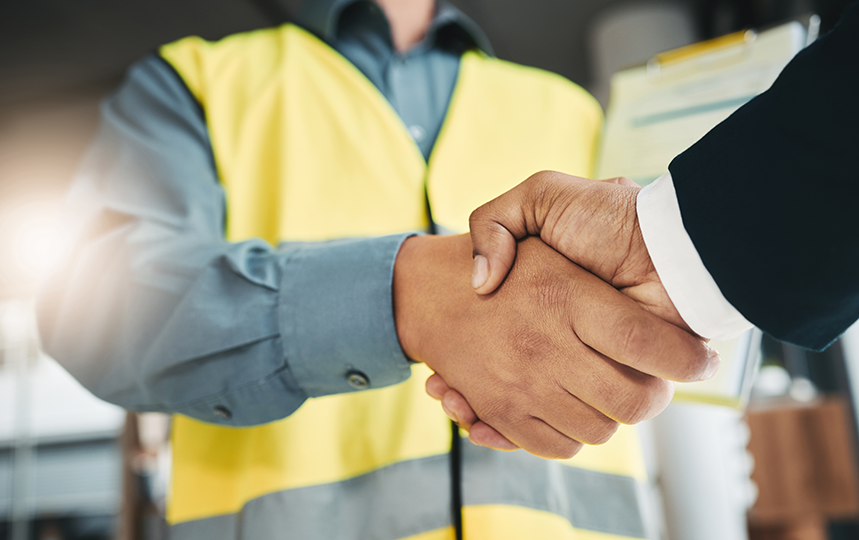 Construction worker in a high-visibility vest shaking hands with a professional in a suit